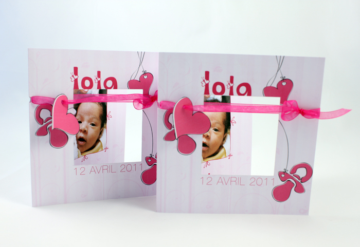 Deux faire-part Lola ouverts côte à côte, ruban rose et cœurs découpés